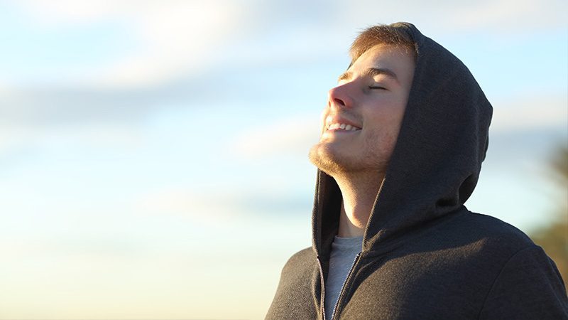 A man smiling while looking up at the sky with his eyes closed