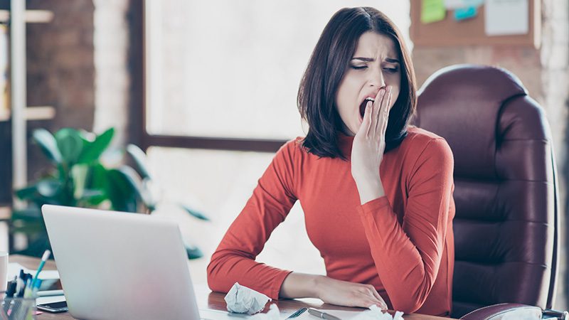 A woman yawning at her desk